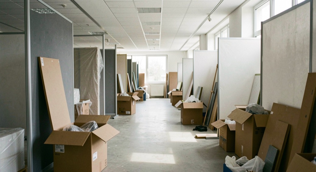 L’allée d’un salon professionnel en cours de montage, stands à demi habillés et caisses de matériel encore ouvertes